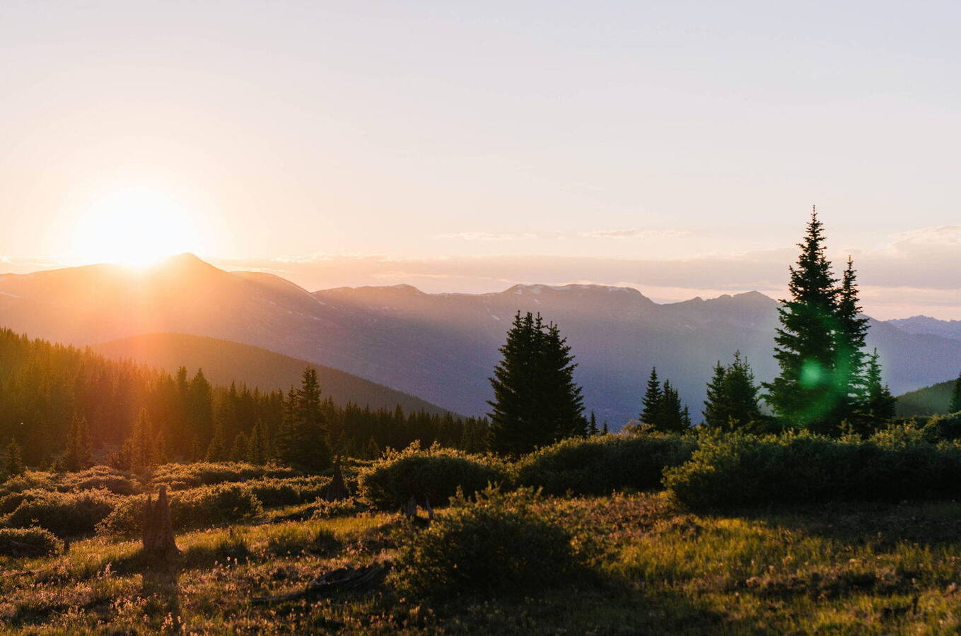 Sunrise over forest landscape: soft morning light illuminates the mountains, offering a calm and picturesque start to the day.