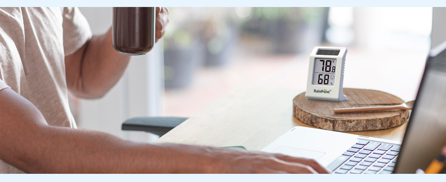 Person holding a mug, using a laptop with a clock nearby.