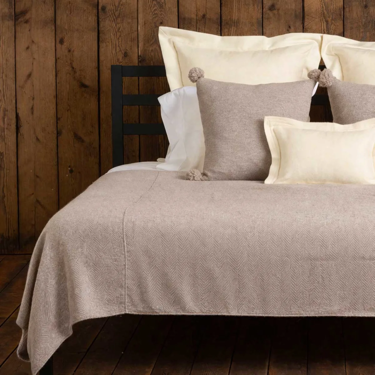 Cozy bed with decorative pillows against a wooden wall.