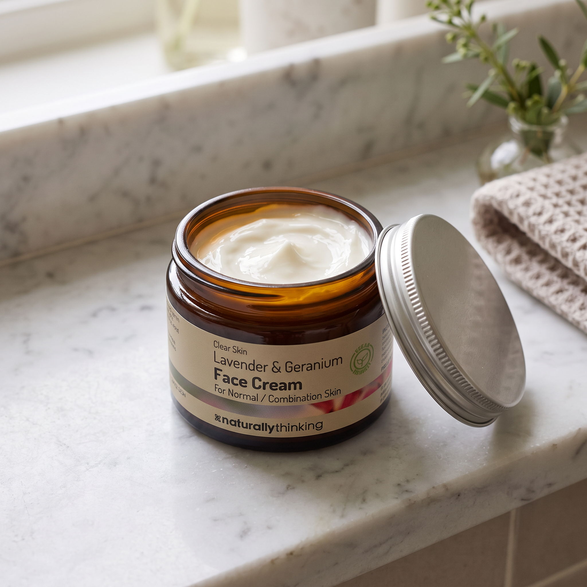 A jar of face cream on a marble countertop.