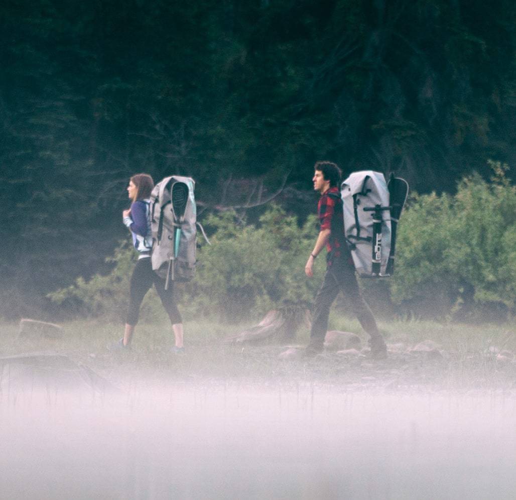 Two people hiking, carrying Travel Bags