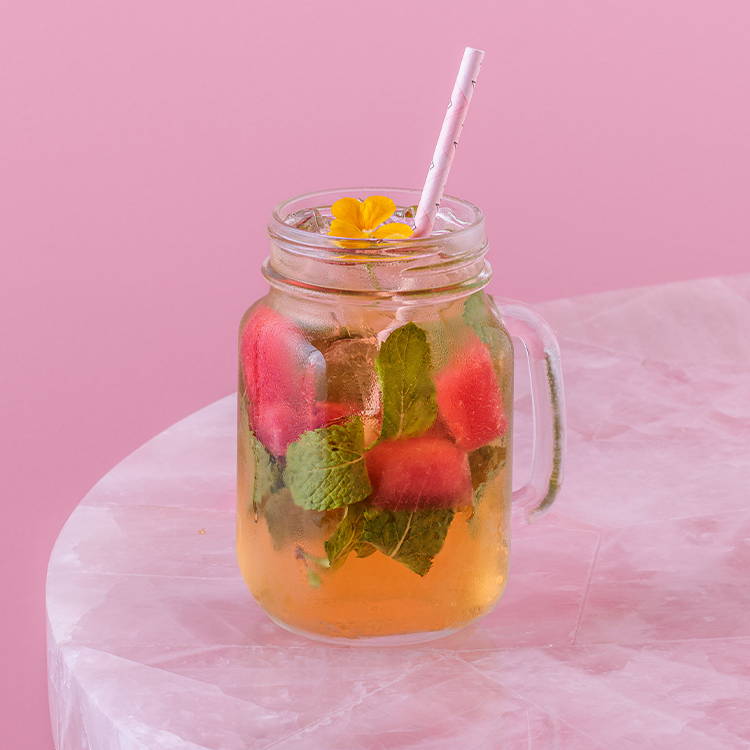 Watermelon green iced tea with mint and pink straw on pink background