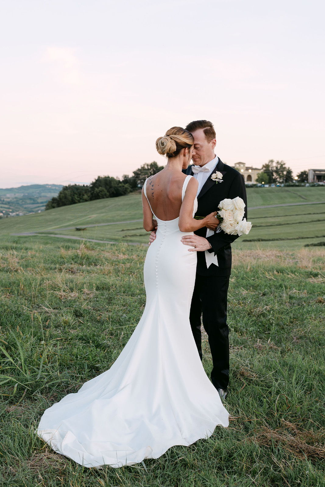 Bride and groom embracing in a scenic outdoor setting during sunset.