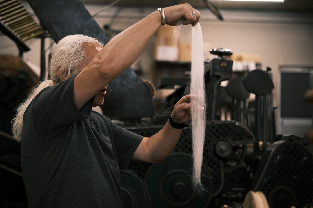 Person inspecting a long sheet of paper in a workshop.