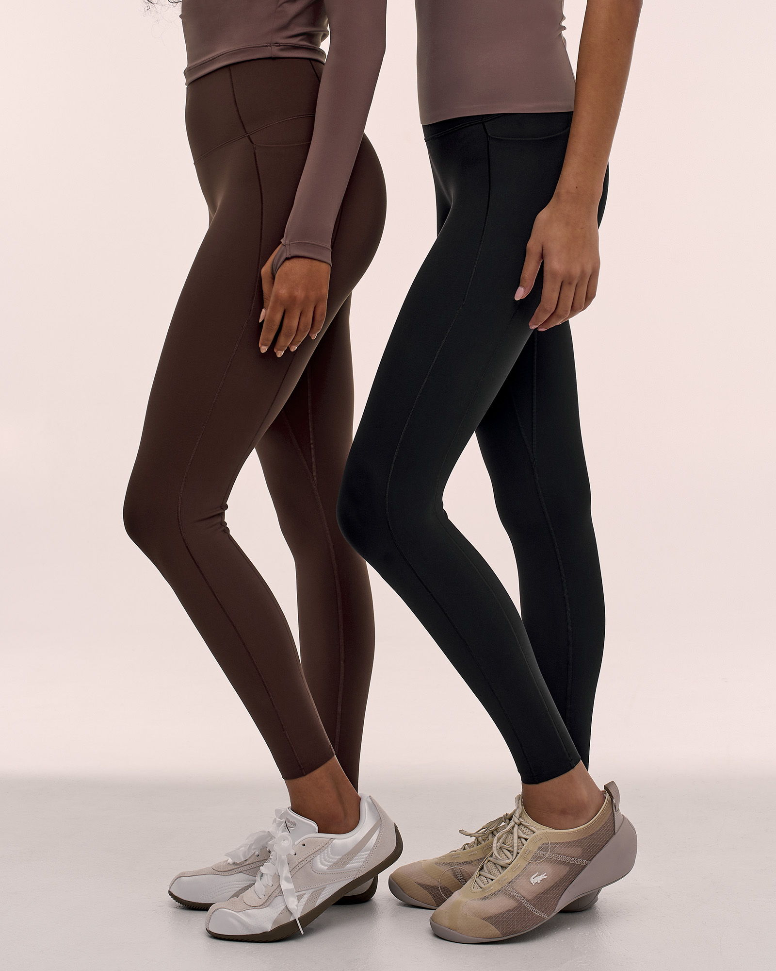 Two women wearing leggings in different colors standing side by side.
