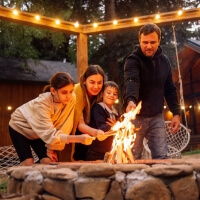 Family gathered around a fire pit, roasting marshmallows in a cozy setting.