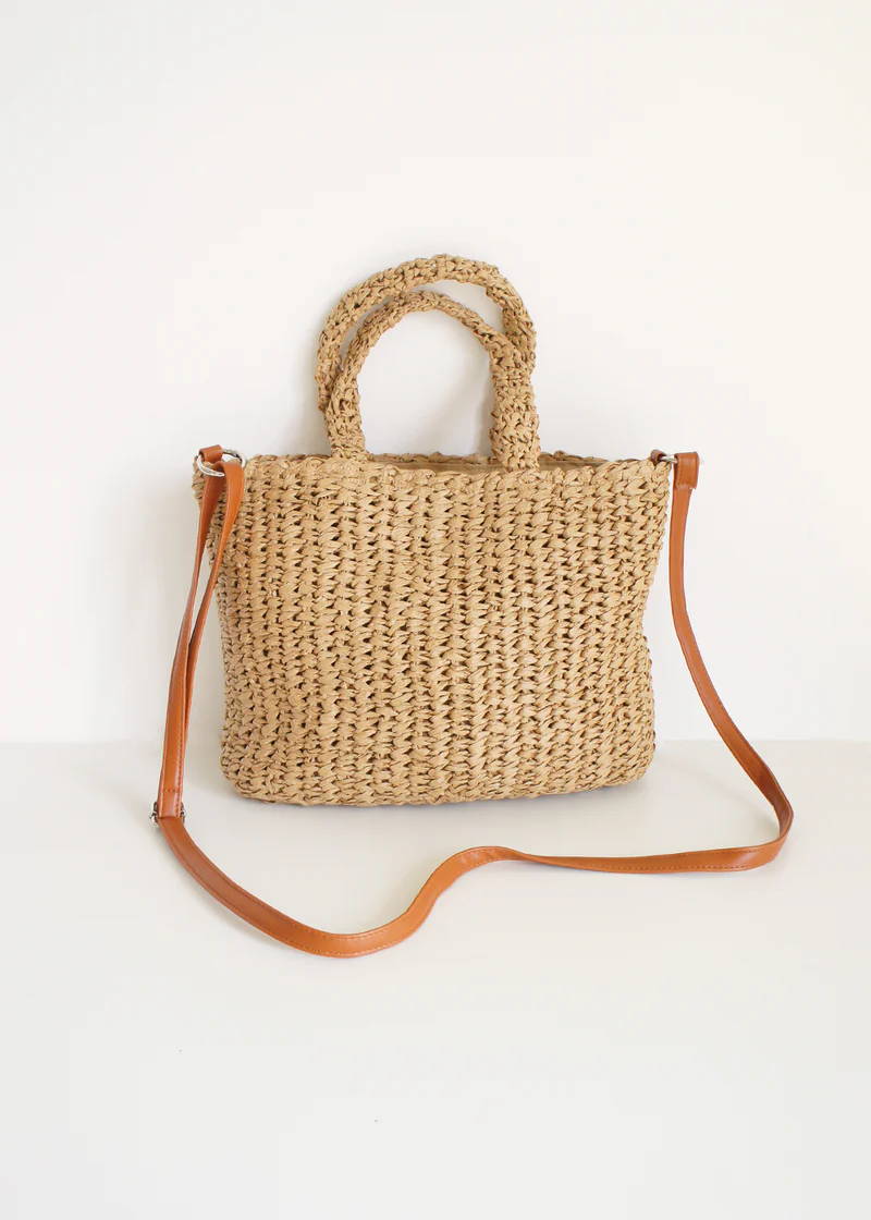 A seagrass/wicker basket bag with hands and a faux leather shoulder strap