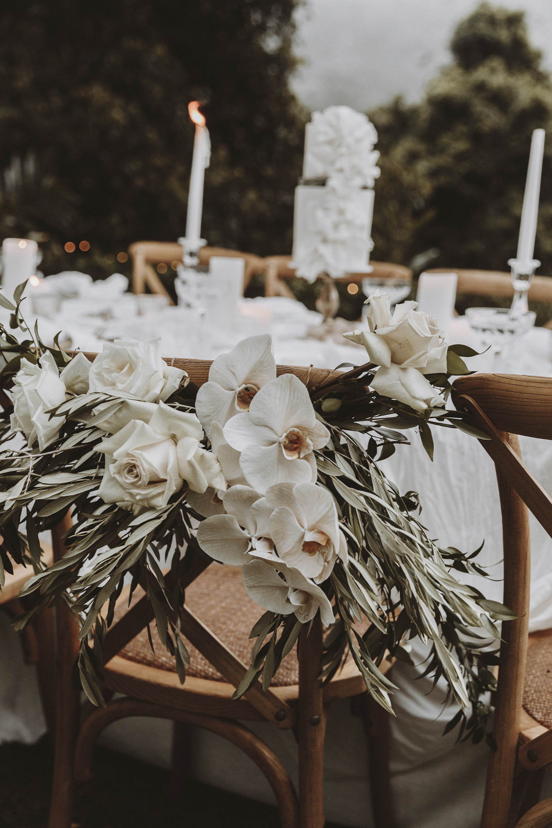 Weiße Blumen und grüne Blätter auf der Rückseite eines hölzernen Hochzeitstischstuhls