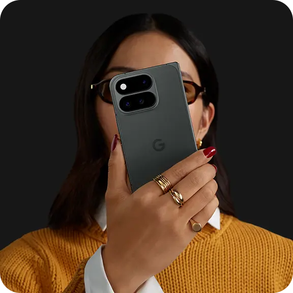 Person holding a smartphone, wearing glasses and a yellow sweater.