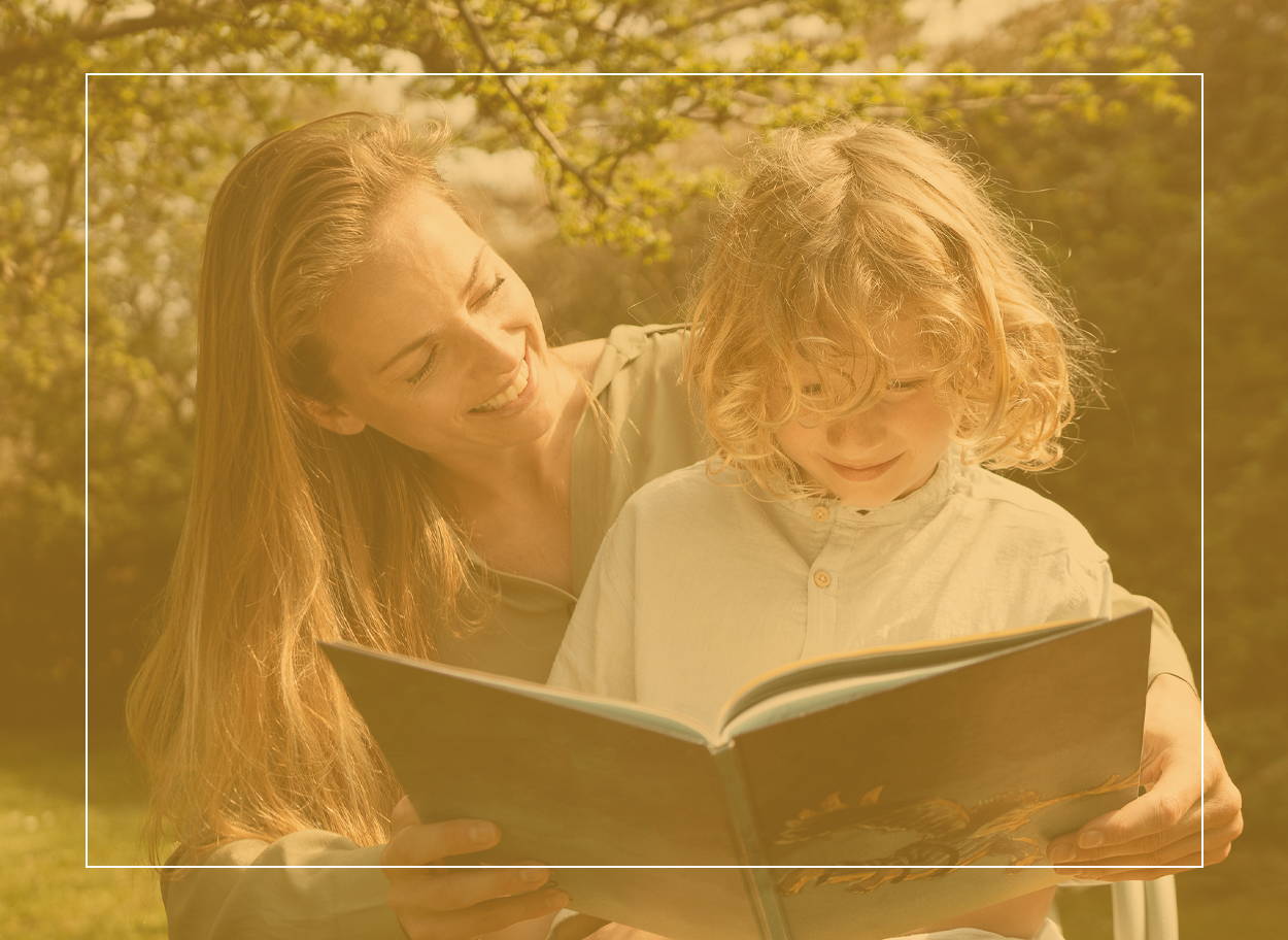 Maminka se synem na klíně si během letního dne venku spokojeně čte knihu – není to taková zábava, pokud má vaše dítě sennou rýmu