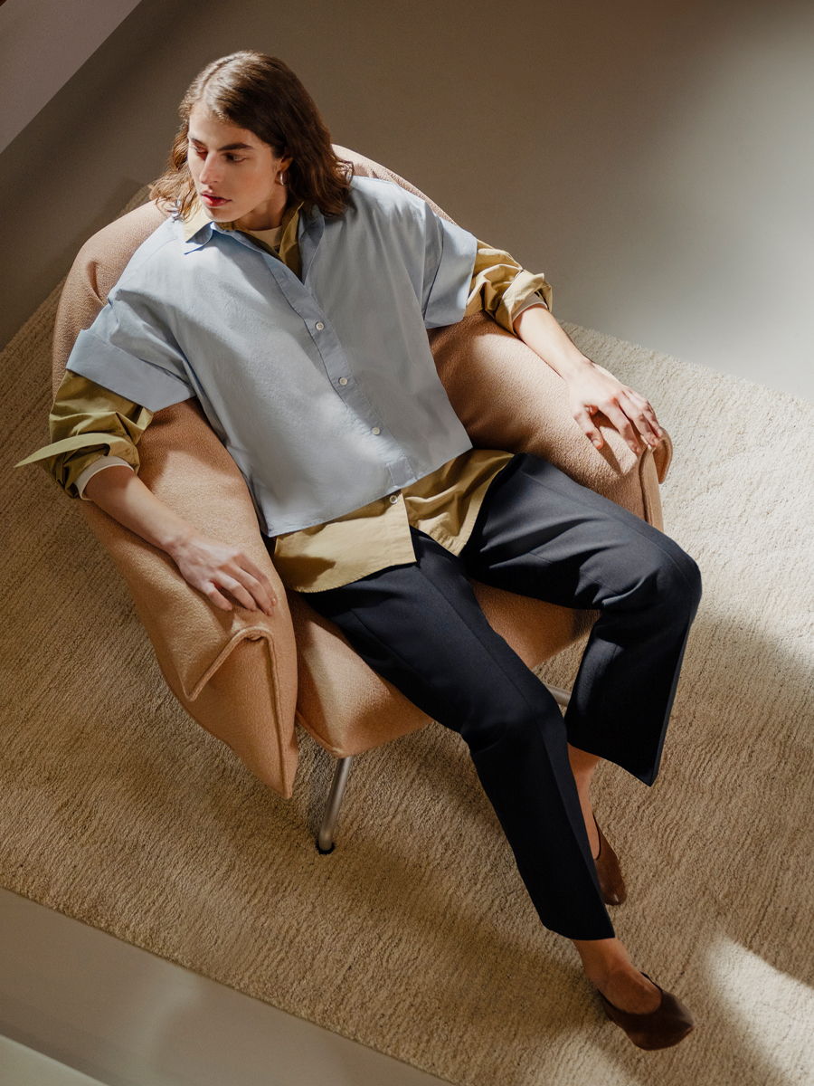 Person sitting on a Bascule chair by Vitra, wearing casual clothing in a stylish setting.