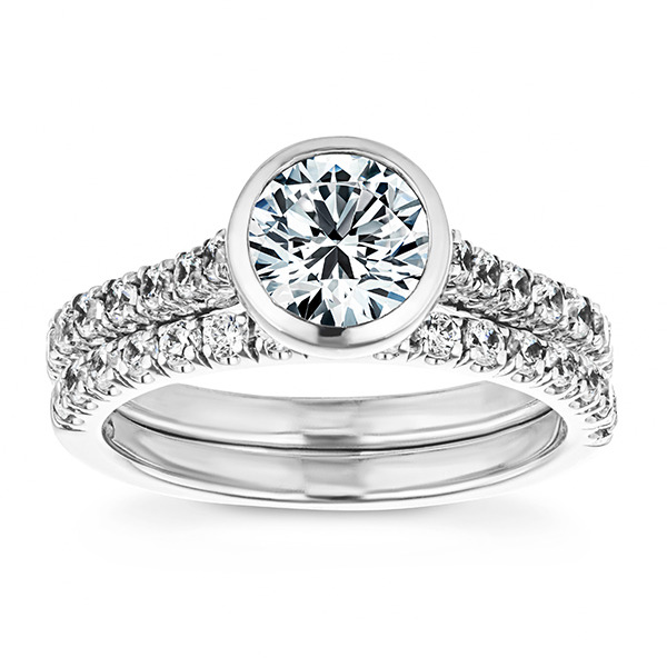 A classy looking white gold wedding set with a bezel engagement ring and diamond accenting on both bands