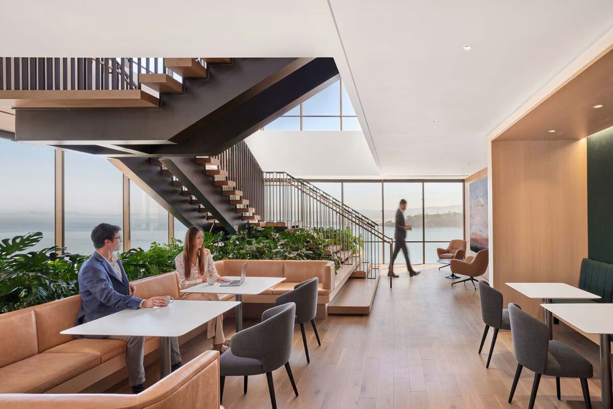 Modern interior of a cafe with seating, plants, and large windows.