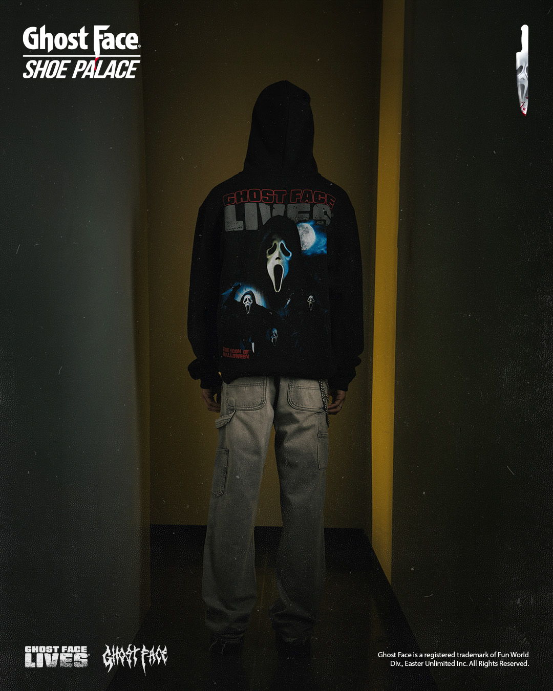 Person wearing a hoodie with Ghost Face design, standing in a dimly lit corridor.