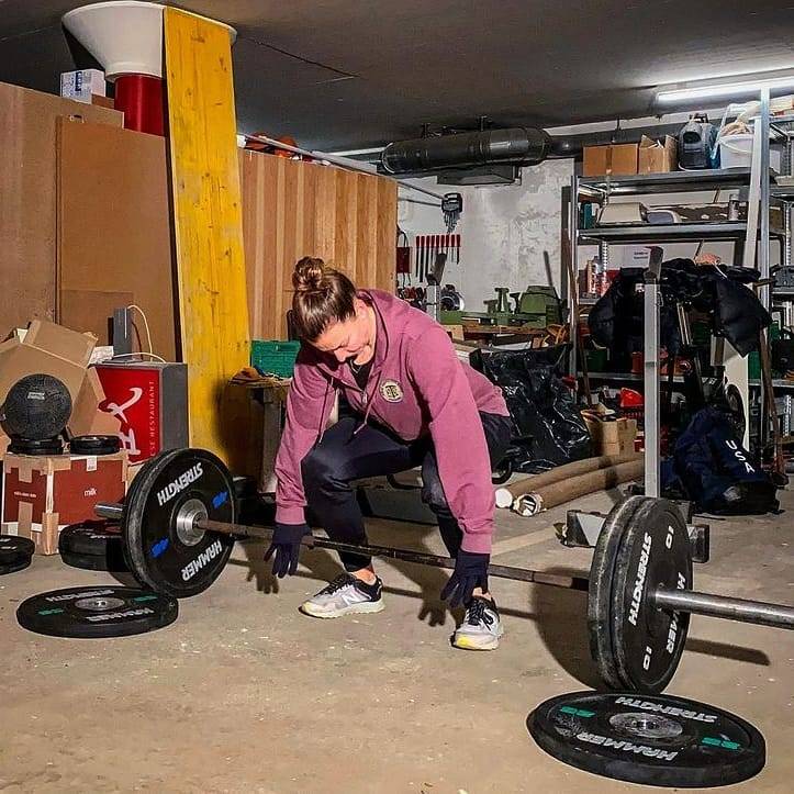 Olympian in garage gym deadlifting with Black Urethane Bumper Plates
