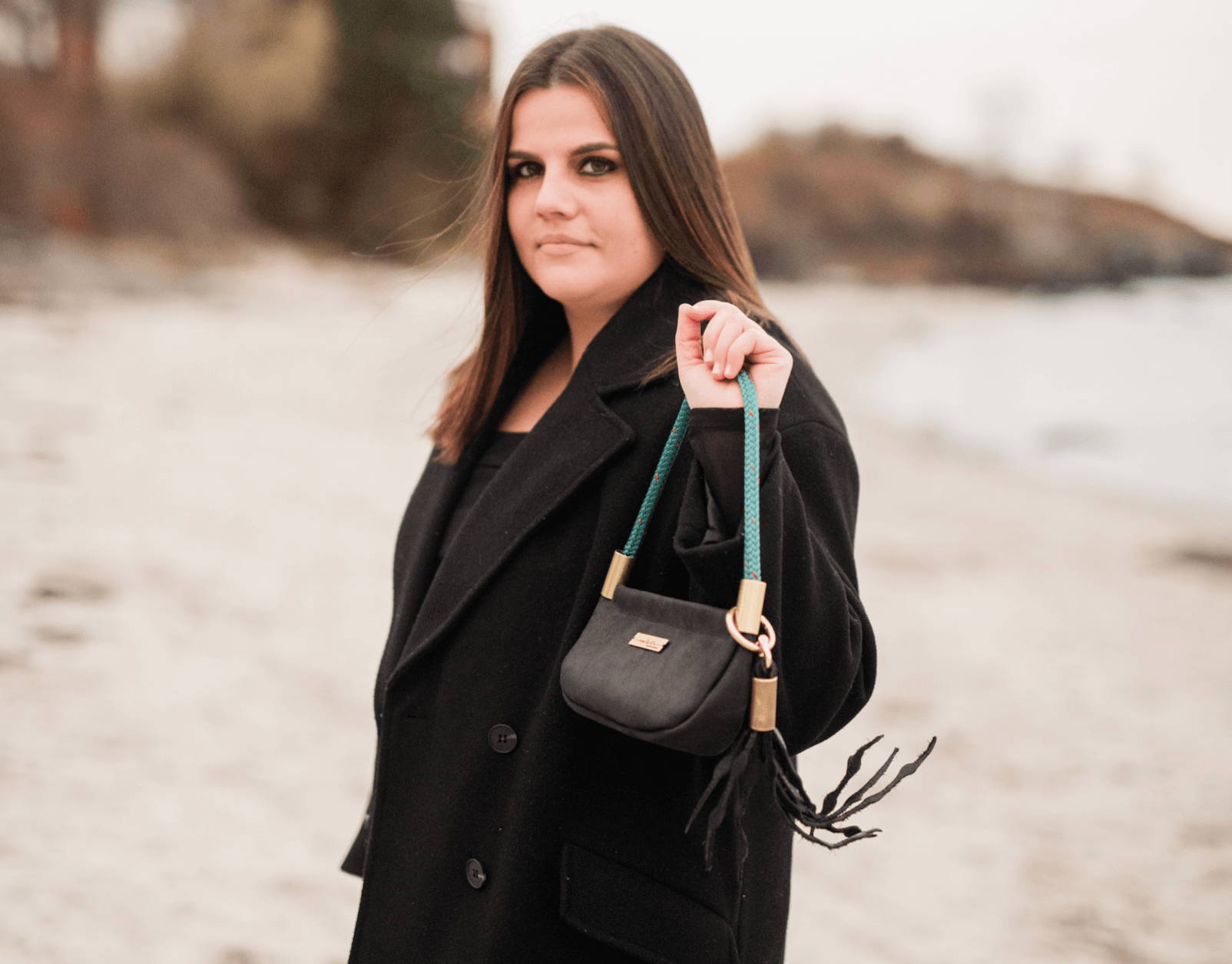 black leather bag on the beach blowing in the wind