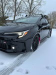 Black GR Corolla parked in snow with headlights on and front-side angle showing Sniper horn install context gallery photo 3