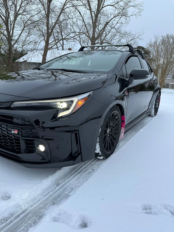 Black GR Corolla parked in snow with headlights on and front-side angle showing Sniper horn install context gallery photo 3