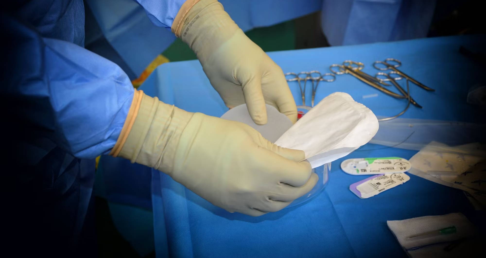 a gloved surgeon opens gauze on a surgical table