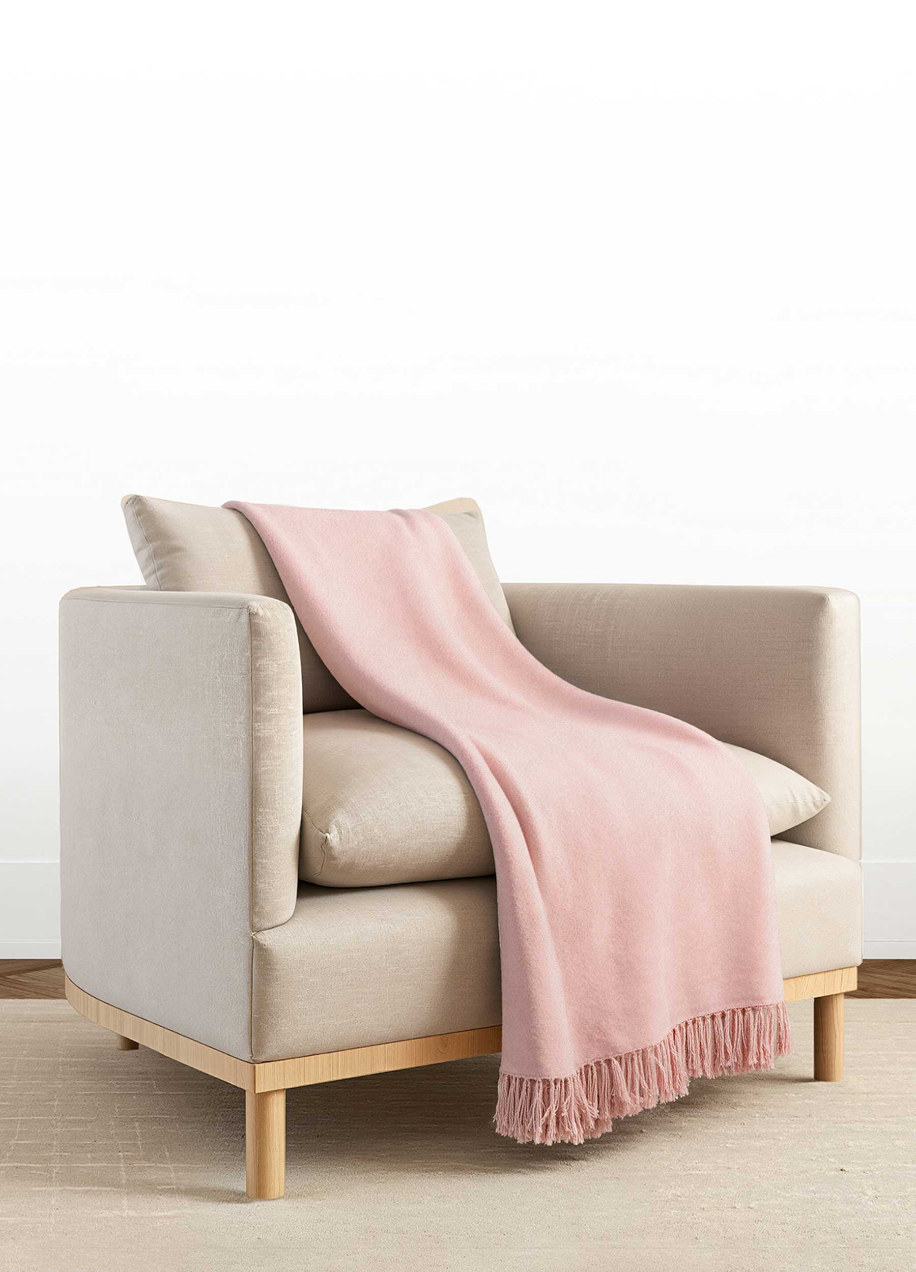 A light pink blanket draped over a modern beige armchair.