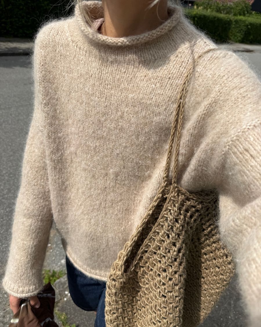 Kvinde iført beige Cloud Sweater med Coast Bag over skulderen 