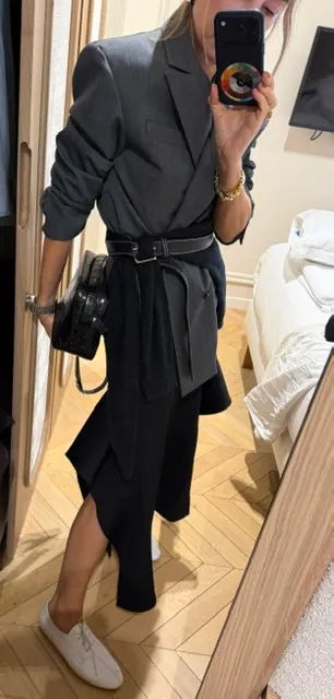 Person taking a mirror selfie in a stylish outfit with a belt and bag.