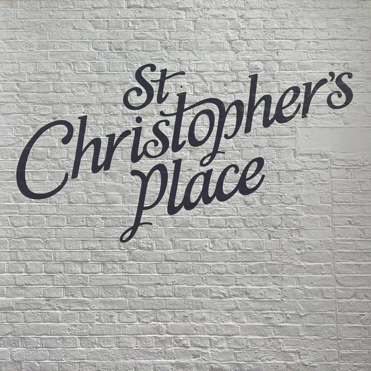 St Christopher's Place pared de ladrillo con logo.