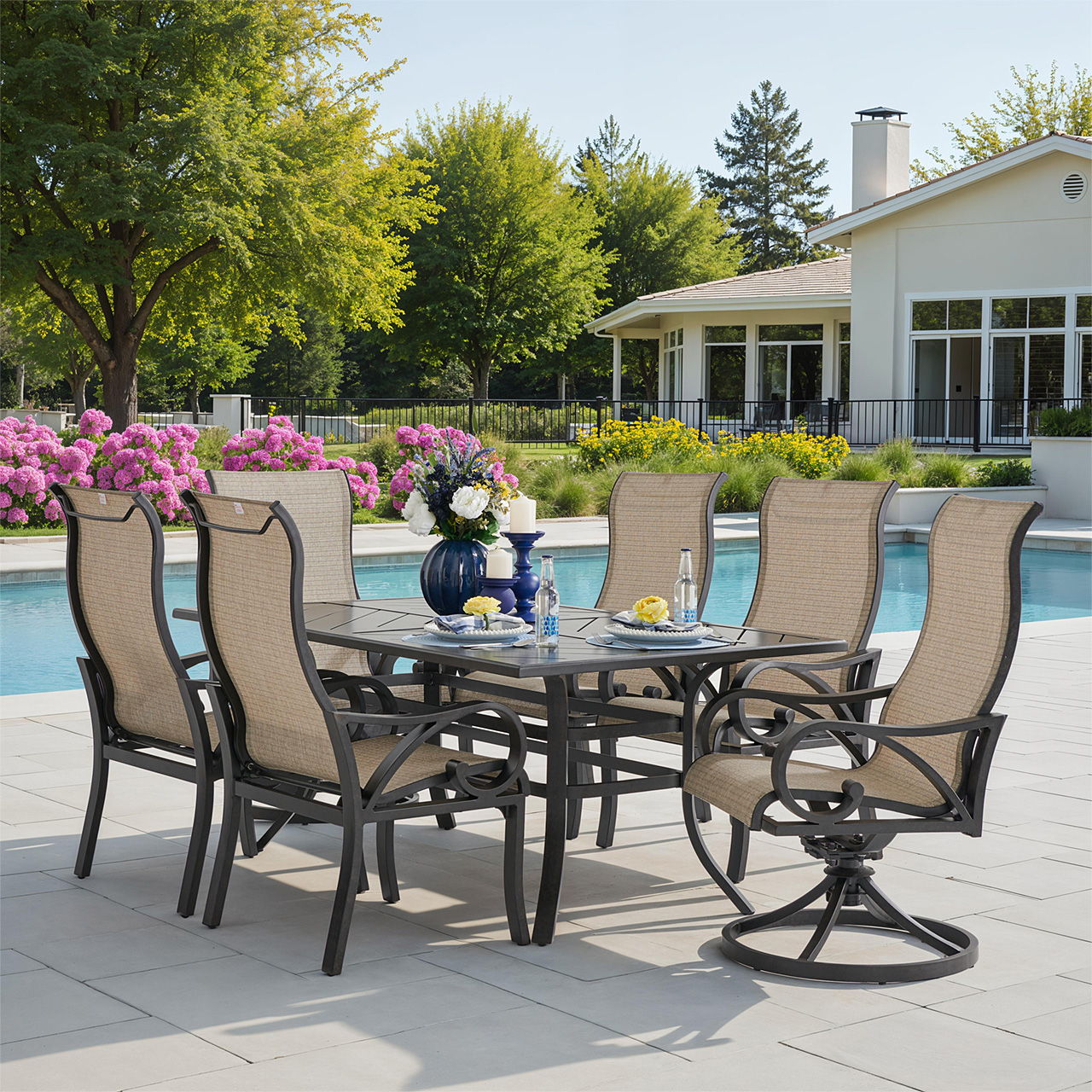 Outdoor dining set by a pool with flowers and trees in background.