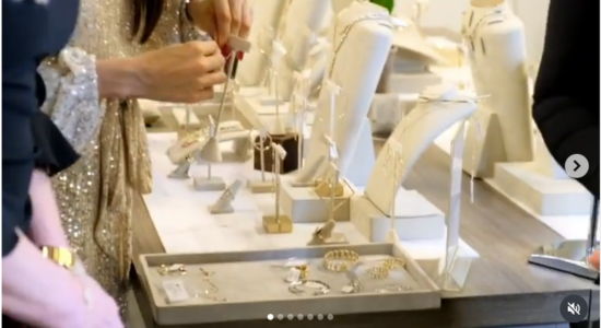 Hands examining jewelry displayed on a table in a boutique.