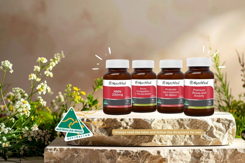 Four bottles of supplements on a stone surface with flowers in the background.