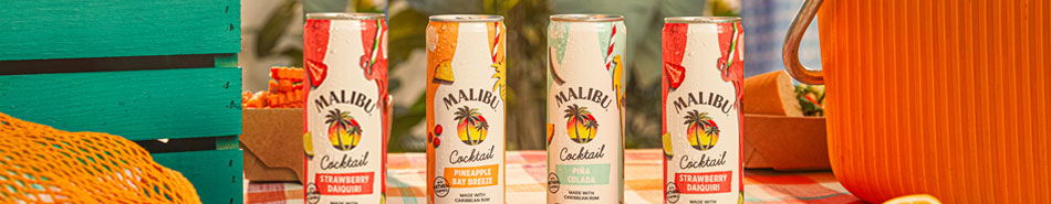 Four beverage bottles displayed with pumpkins in a colorful setting.