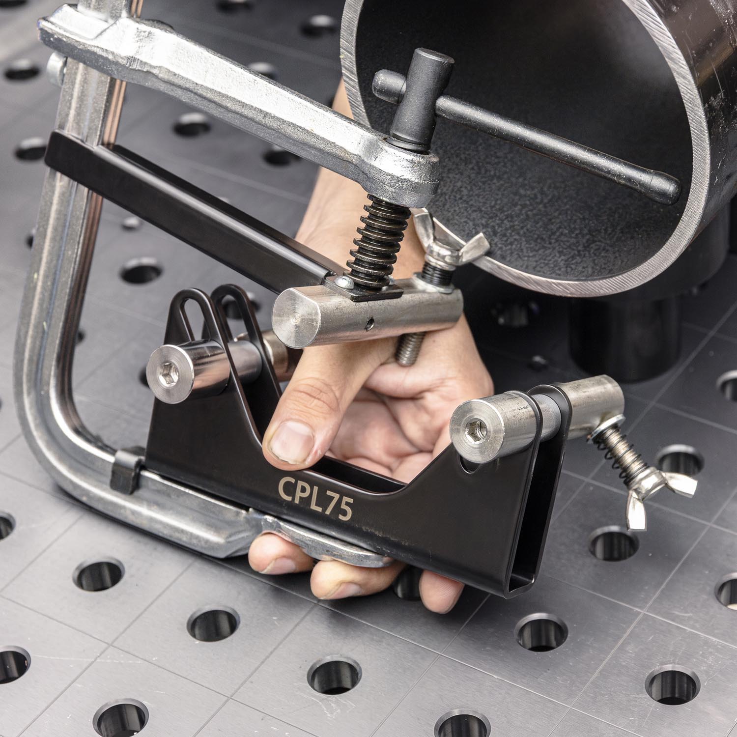 A hand holding a clamping tool on a work surface.