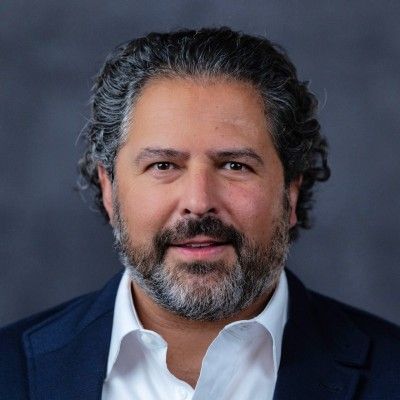 Businessman with curly hair, wearing a suit and smiling.
