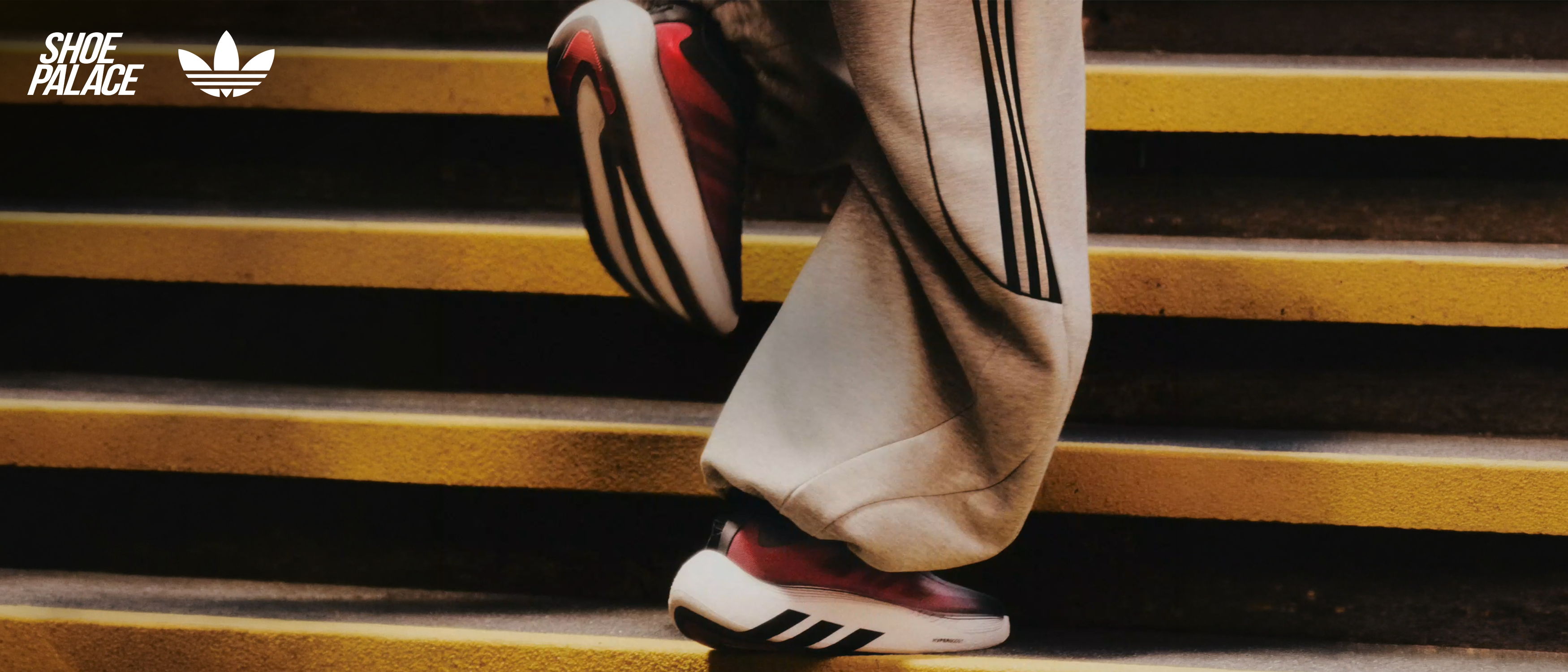 Person wearing Adidas shoes walking down stairs.