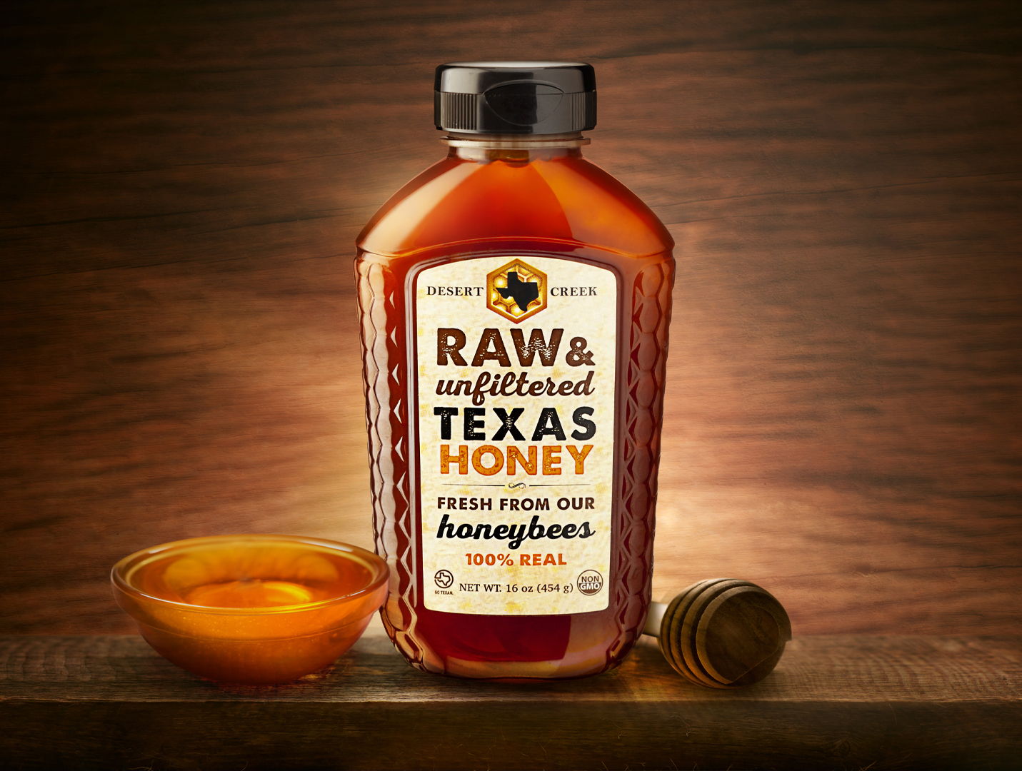 Bottle of raw Texas honey next to a small bowl of honey.