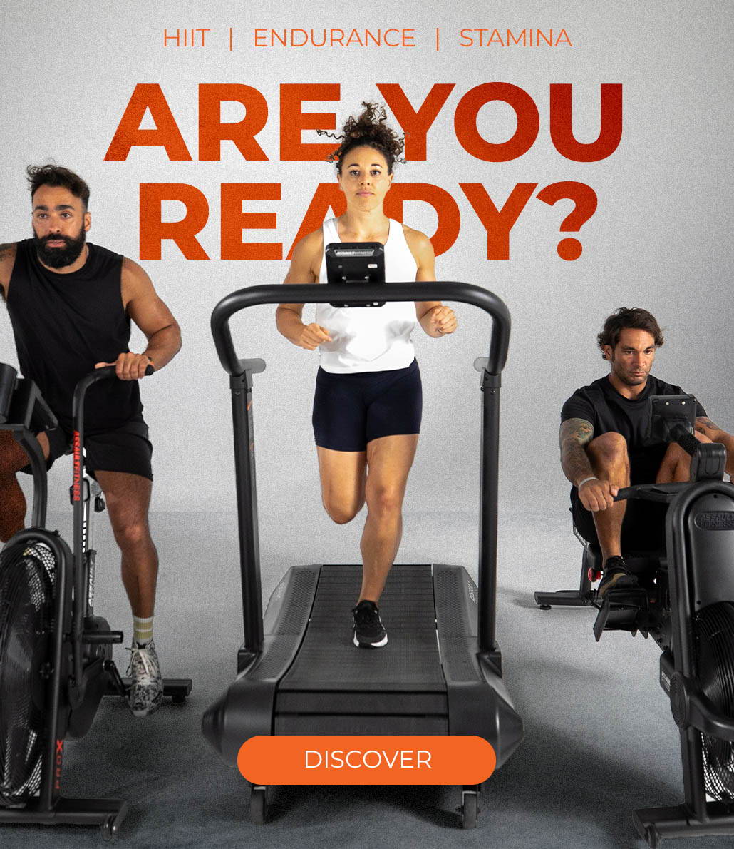 High-intensity workout equipment from Assault Fitness, known for catering to HIIT, endurance, and stamina training. Central to the visual is a dynamic display of an Assault Fitness treadmill, air bike, and rowing machine, each occupied by focused athletes mid-workout. The commanding orange text 