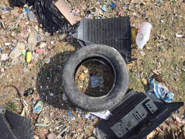 A rubber car tire in the middle of a garbage site in the Dominican Republic before it becomes upcycled into Brave Soles leather shoes.