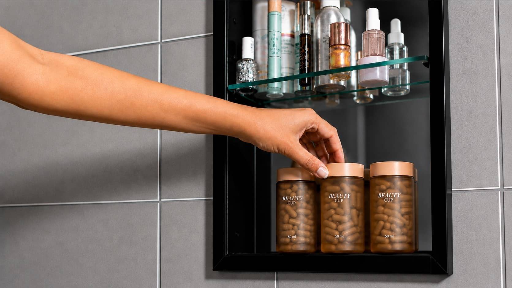 A hand reaches into a medicine cabinet to pick up one of three supplement jars, with skincare bottles on the shelf above.