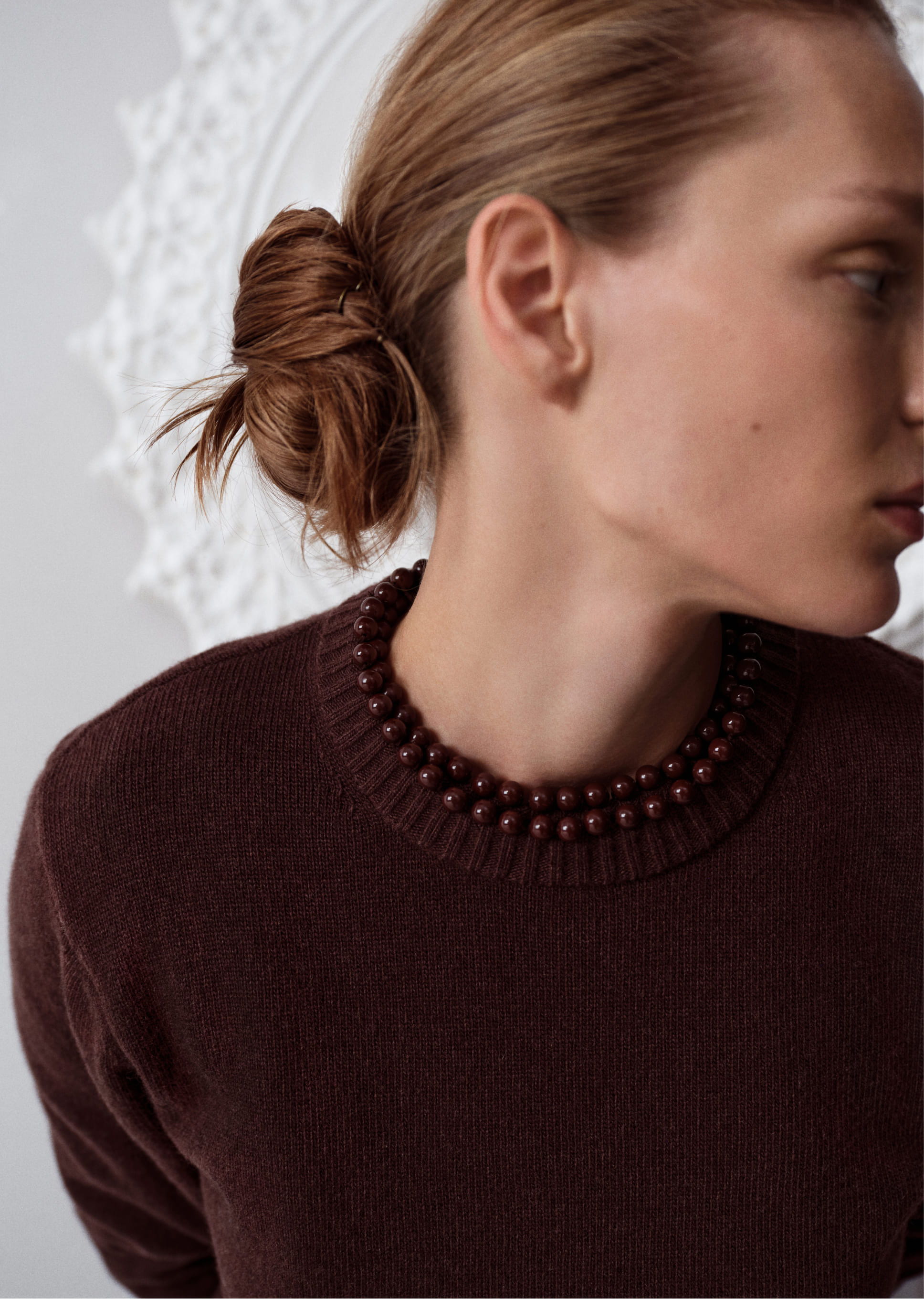 Profile of a woman with a bun wearing a dark sweater.