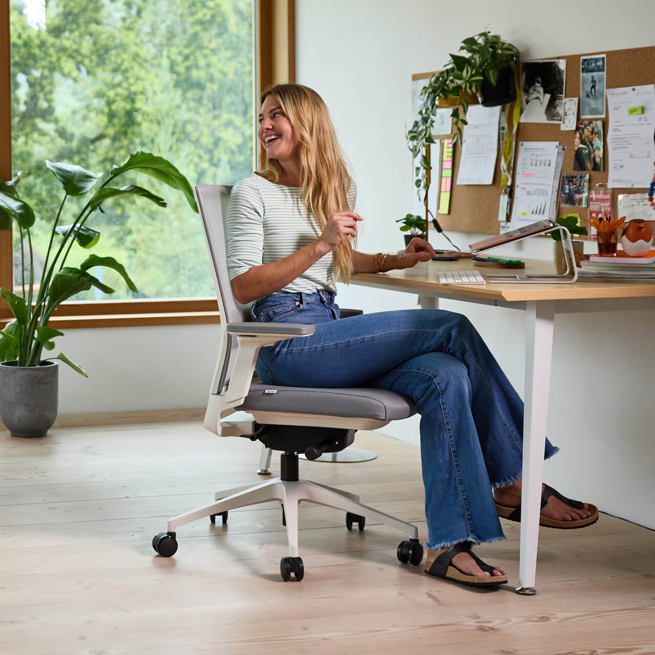 Une femme blonde est assise sur un Ofinto Active blanc Active utilise le mécanisme innovant d'inclinaison de l'assise de la chaise de bureau.