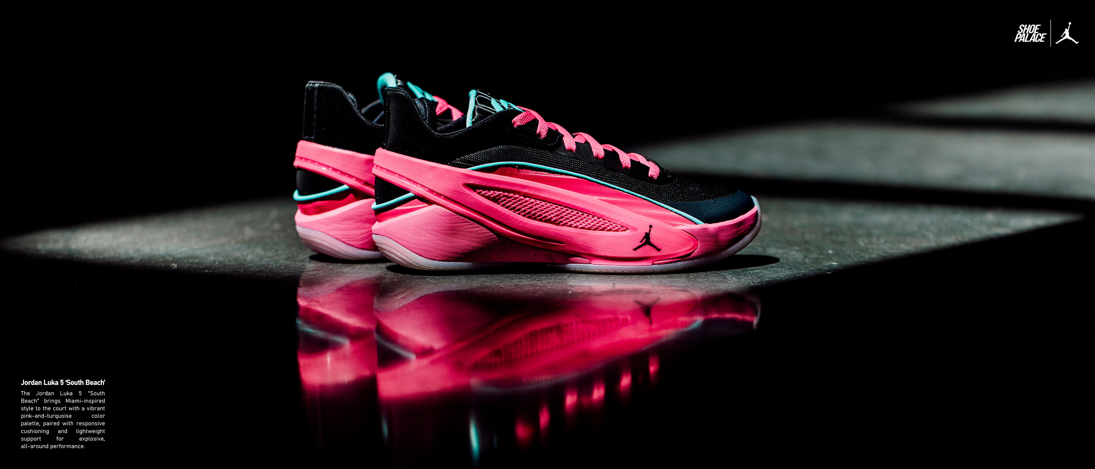 A pair of pink and black athletic shoes on a reflective surface.