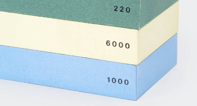 A vertical stack of 220-grit, 1000-grit, and 6000-grit sharpening stones, showing the durable 20 millimeter thickness of each.