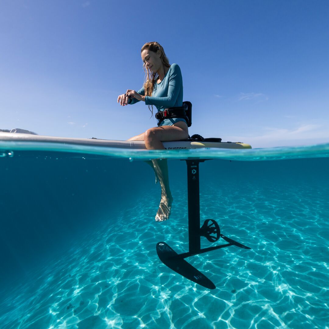 Person on a hydrofoil board above clear blue water.