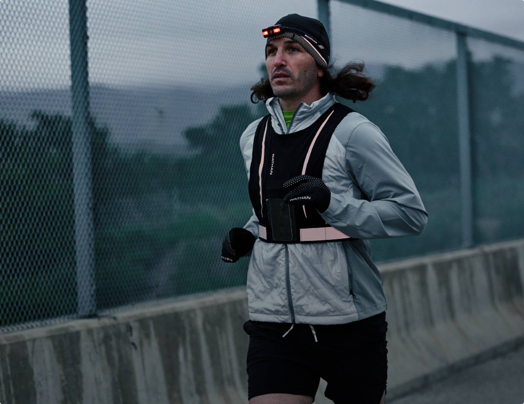 Male road running in an early morning setting while wearing Nathan safety gear