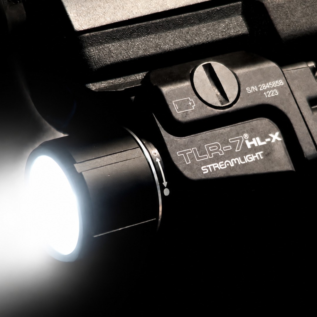 Black flashlight with a bright light beam, labeled TLR-7 HL-X.