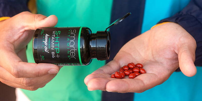 Opened smarter 5-HTP bottle in hand, pouring vitamins into other hand.
