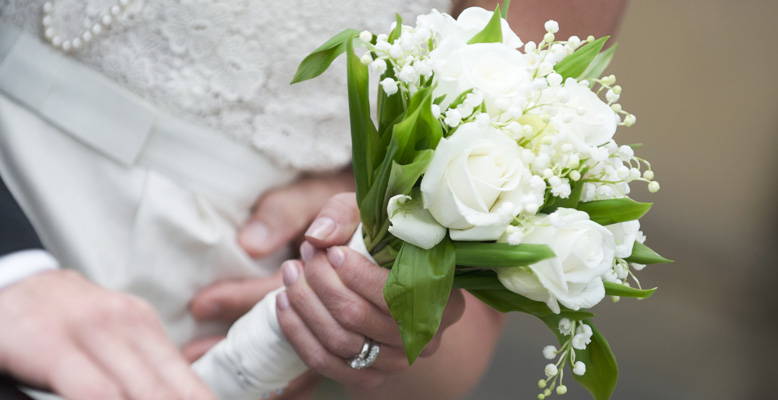 Bride holding a white and green flower bouquet.
