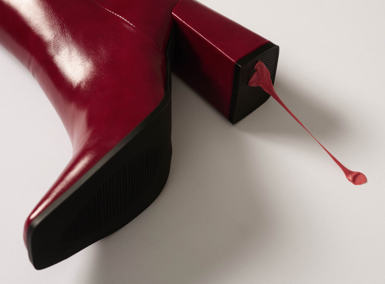 A red high heel shoe next to a spilled nail polish.
