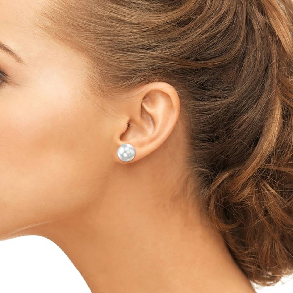 Model wearing a large pair of pearl stud earrings