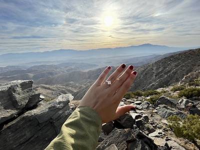 hand with engagement ring overlooking mountain